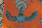 Wat Xieng Thong temple in Luang Prabang, Laos. Detail of the famous tree of life mosaic of the back wall of the sim, in colored glass on a dark red background.